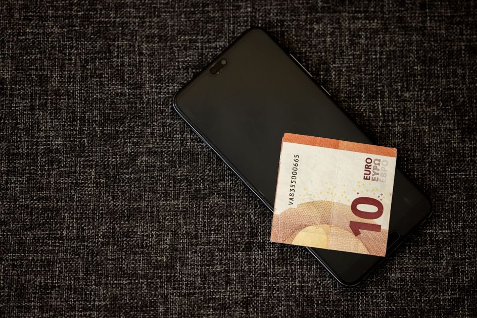Person sitter med mobil och räkningar och funderar på att låna pengar utan avslag